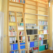 Bücherwand in Kiefer, beleuchtet, mit Bibliotheksleiter